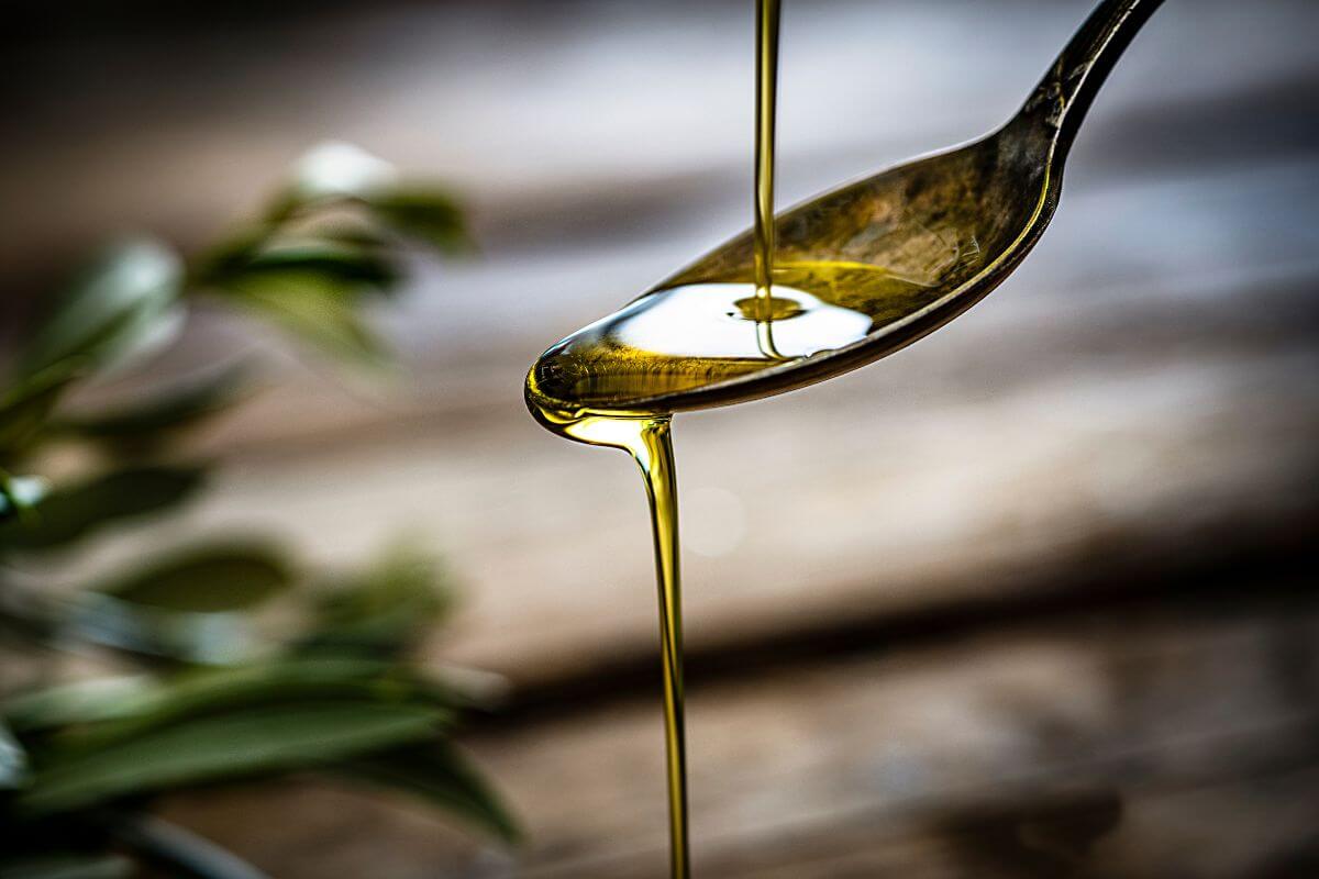 olivsen-spoon-with-olive-oil-in-front-of-wood